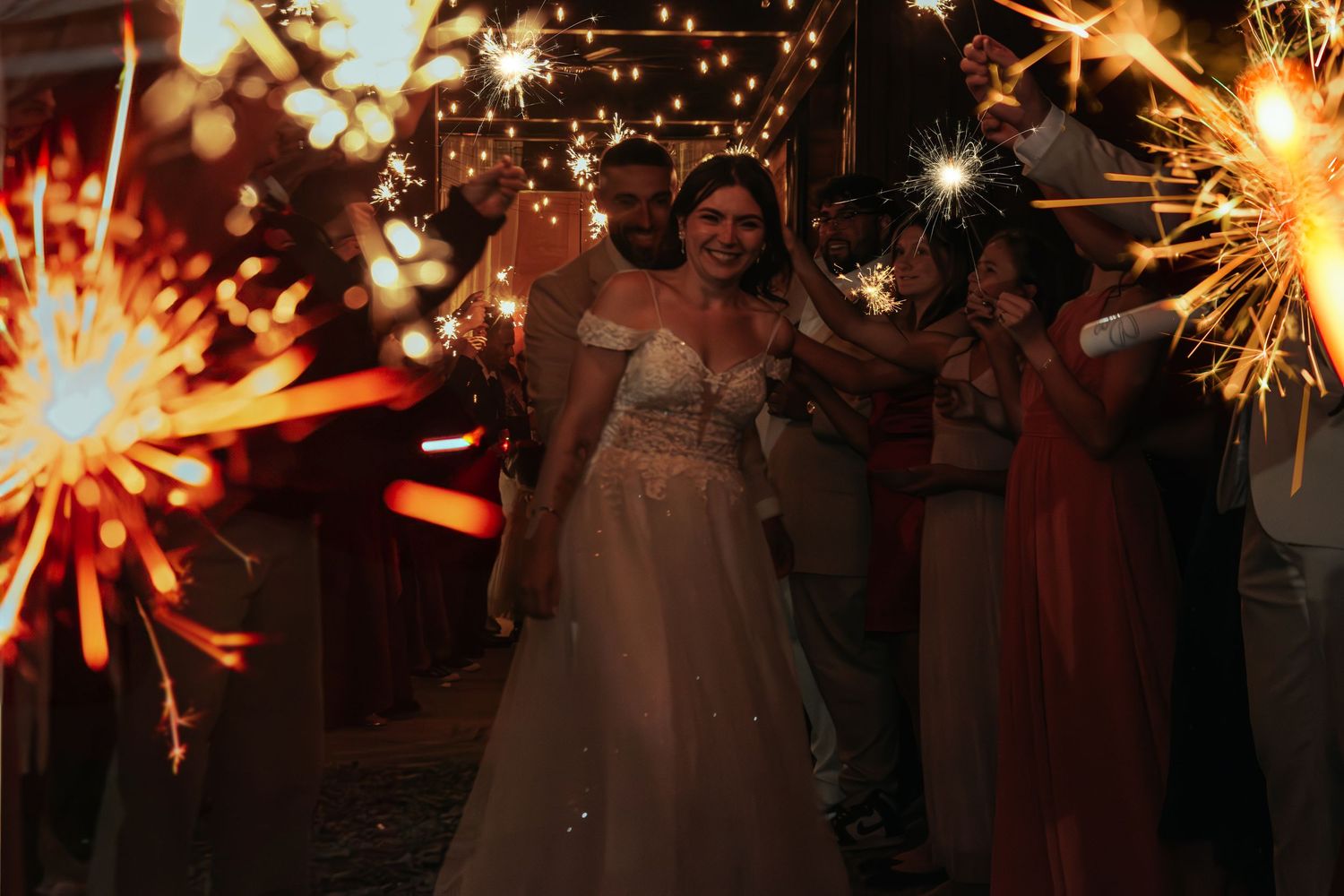 Bride walks through a sparkler exit with bridesmaids at her wedding reception.
