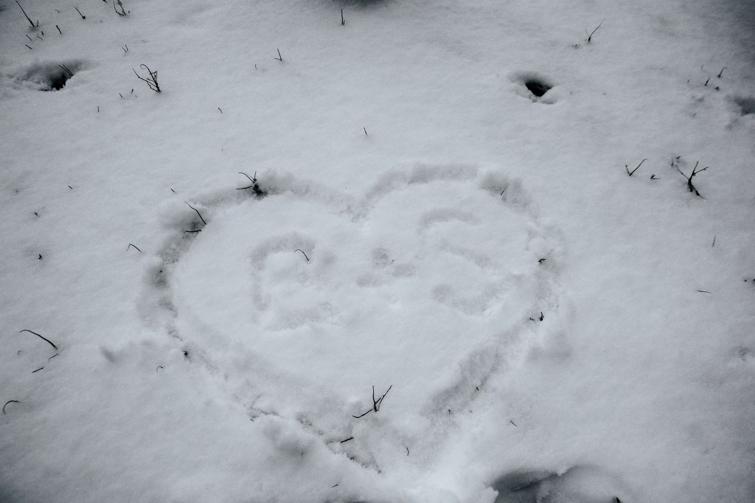 Heart shape with initials B and S drawn in fresh white snow outdoors.