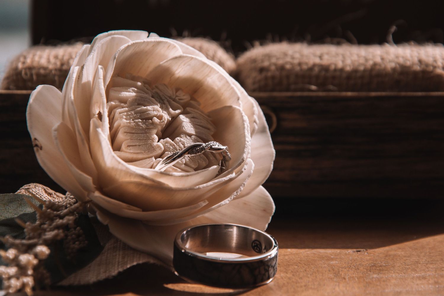 Elegant white rose with wedding rings on a wooden surface for a romantic bridal detail shot.