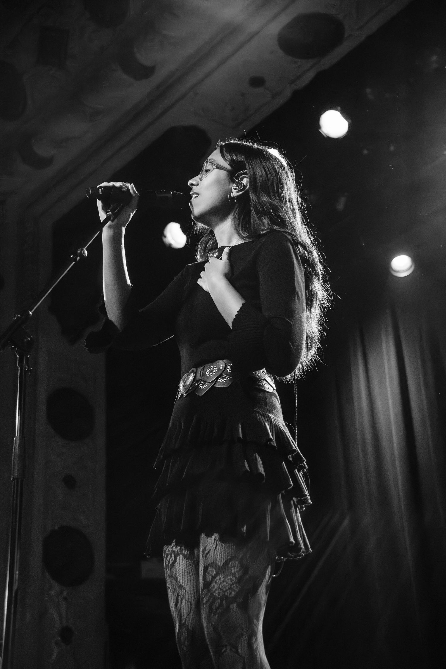 A series of black and white concert photos showing a performer singing on stage with dramatic lighting.