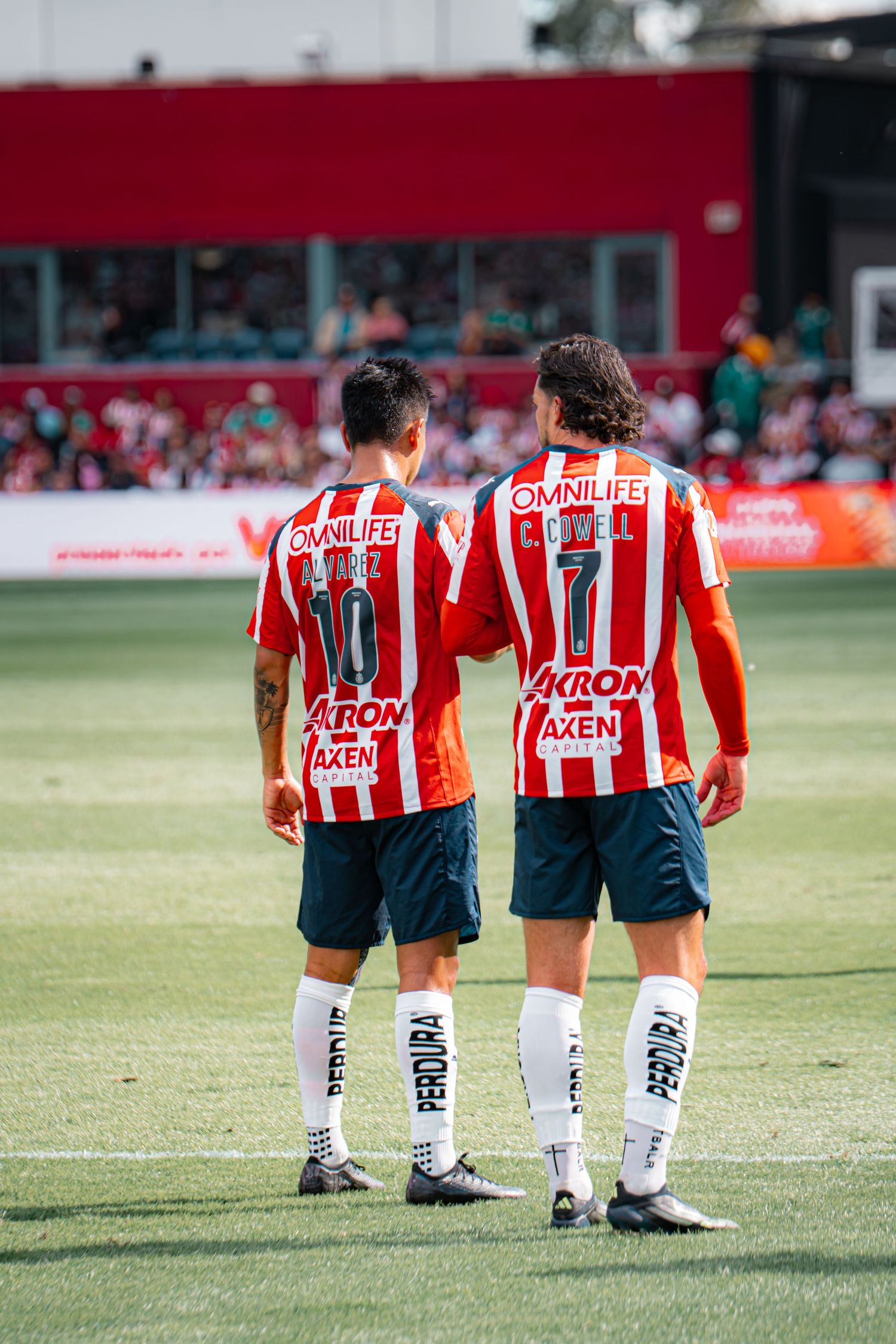 Soccer players in red and white striped jerseys walk across the field during a match.