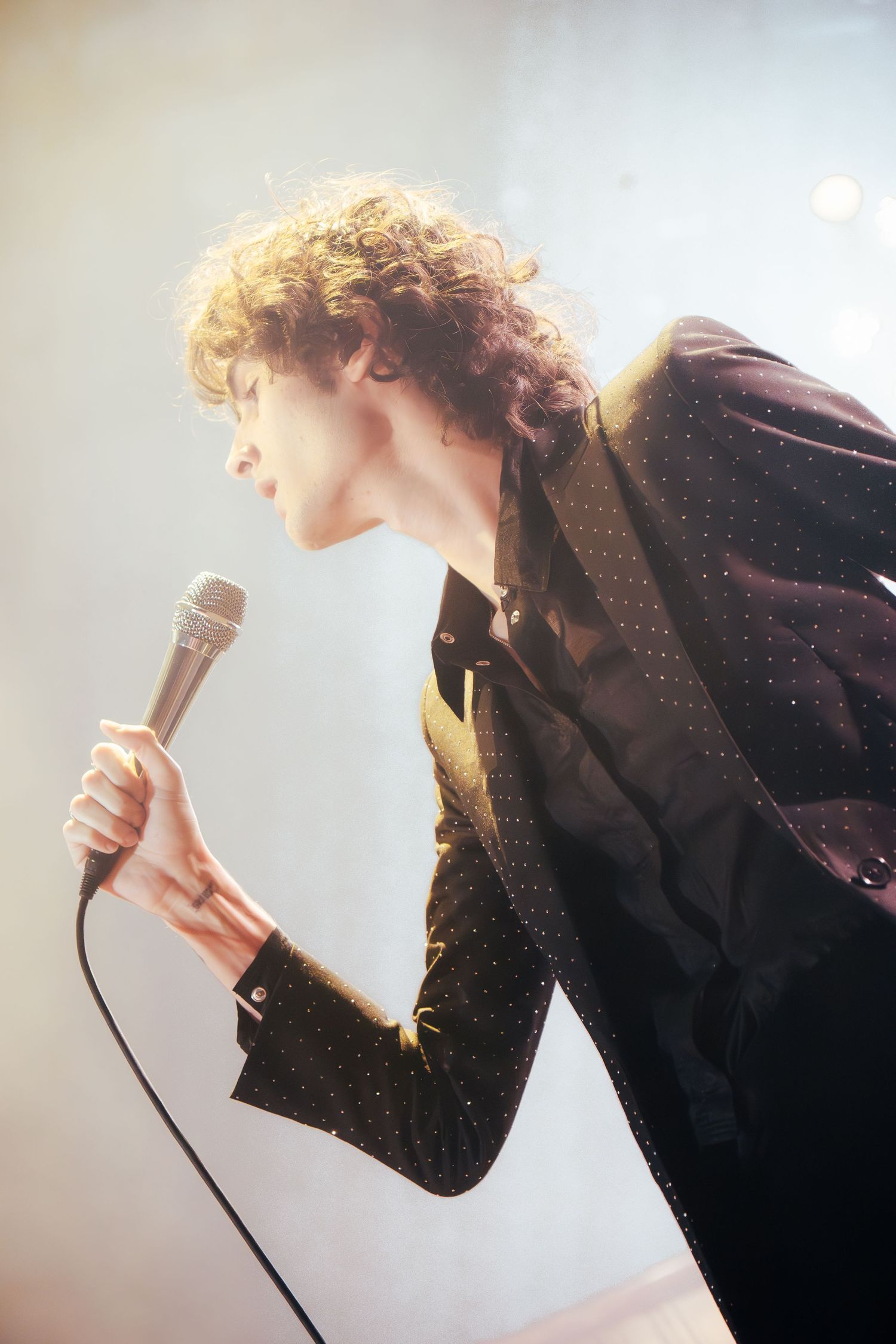 A series of dynamic performance photos showing a singer in silhouette against bright stage lighting.