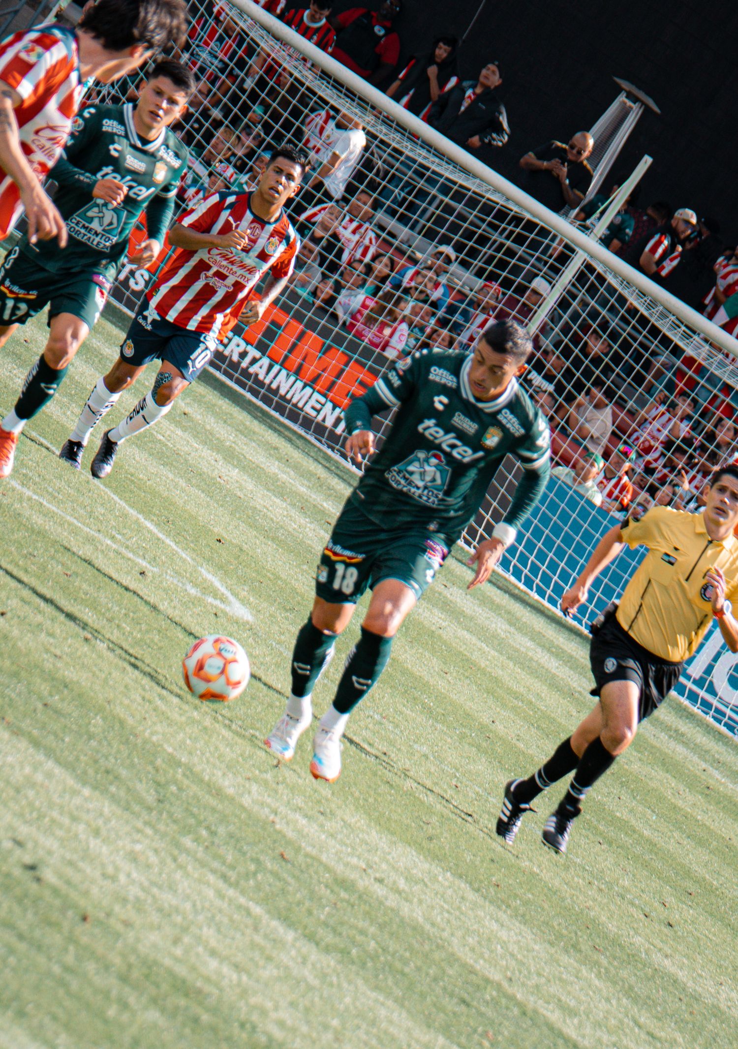 Soccer players running across field with goal net visible in background during match.