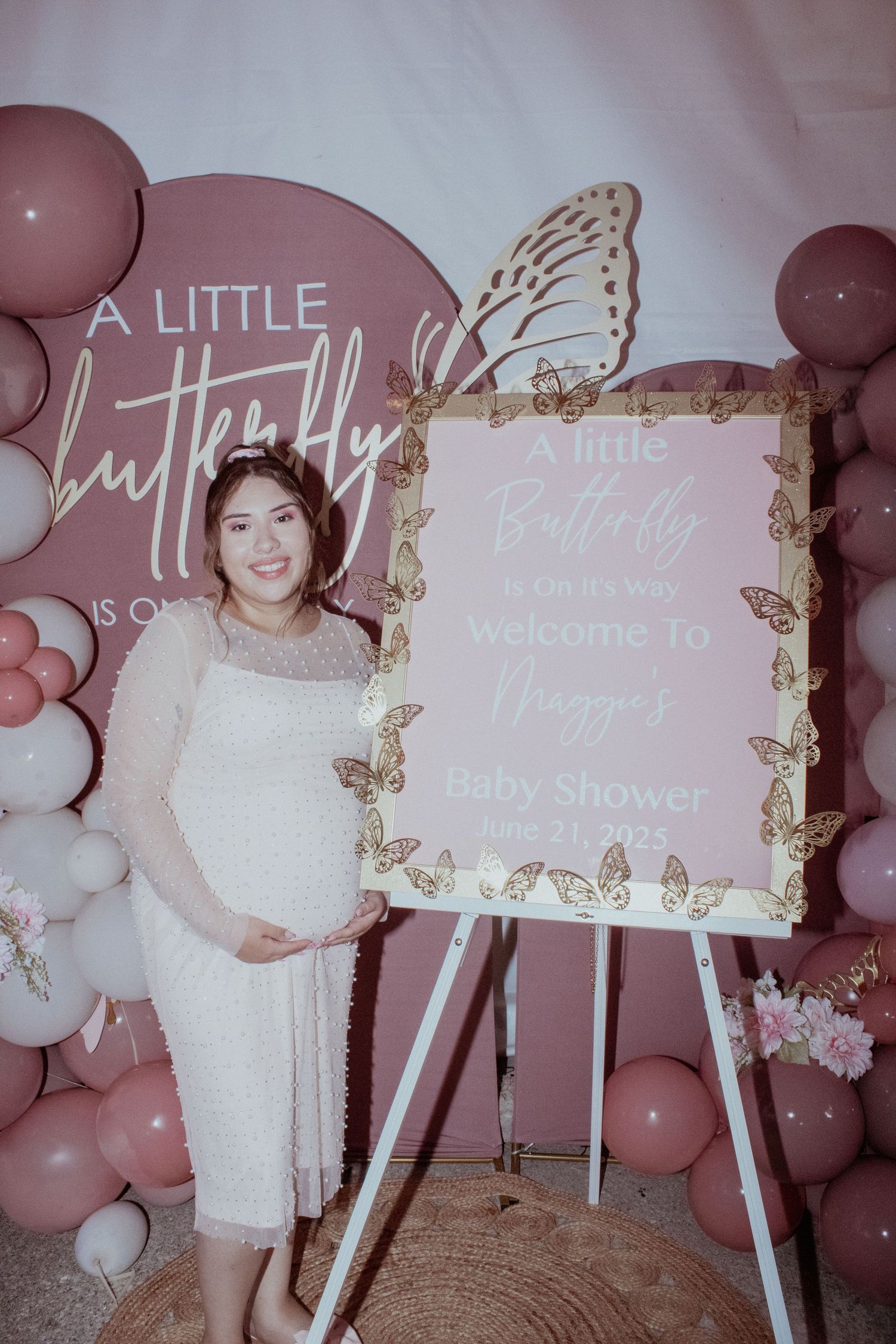 Baby shower signage with butterfly motifs and pink balloon decorations.