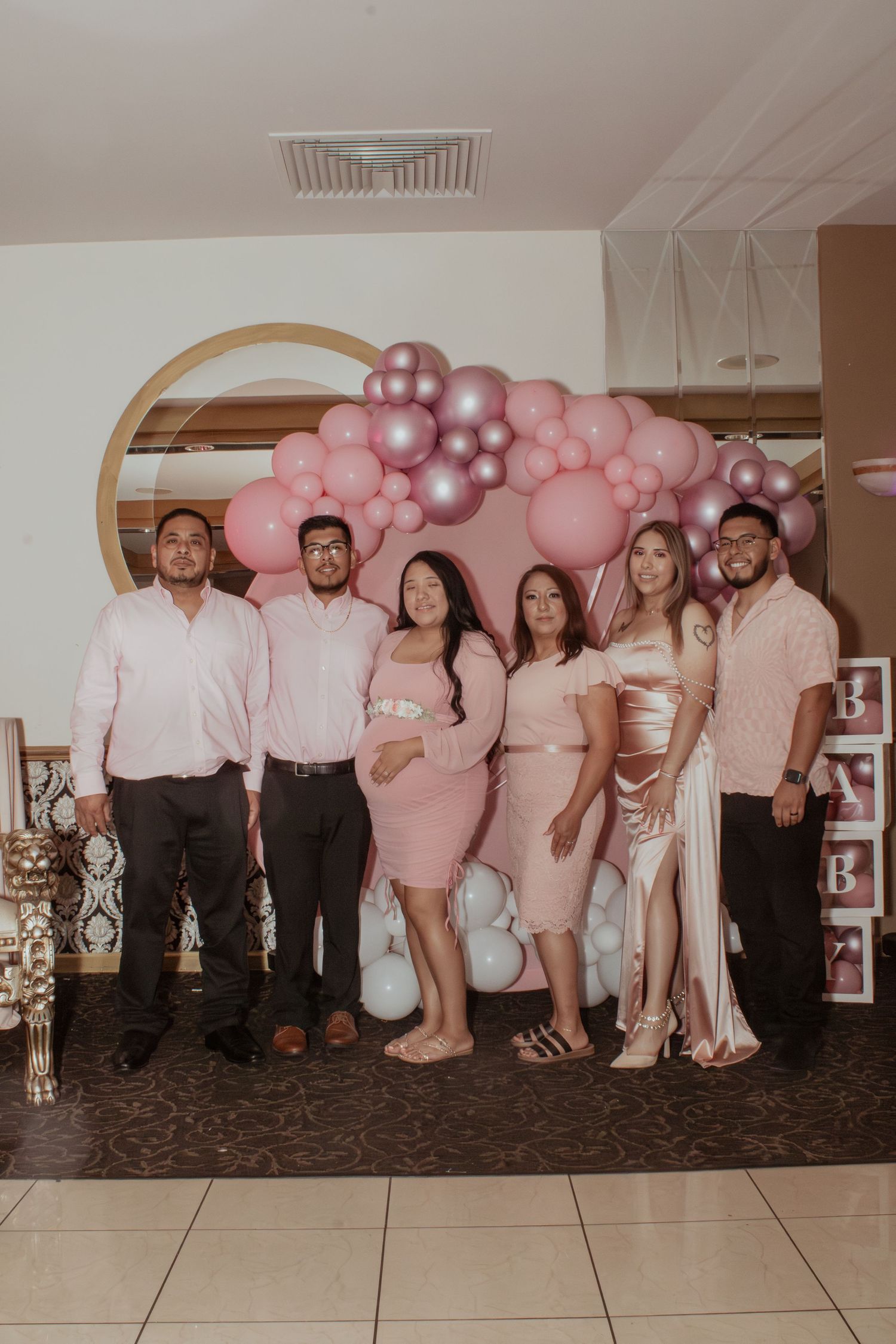 Group photo with pink balloon arch backdrop at a celebration event.