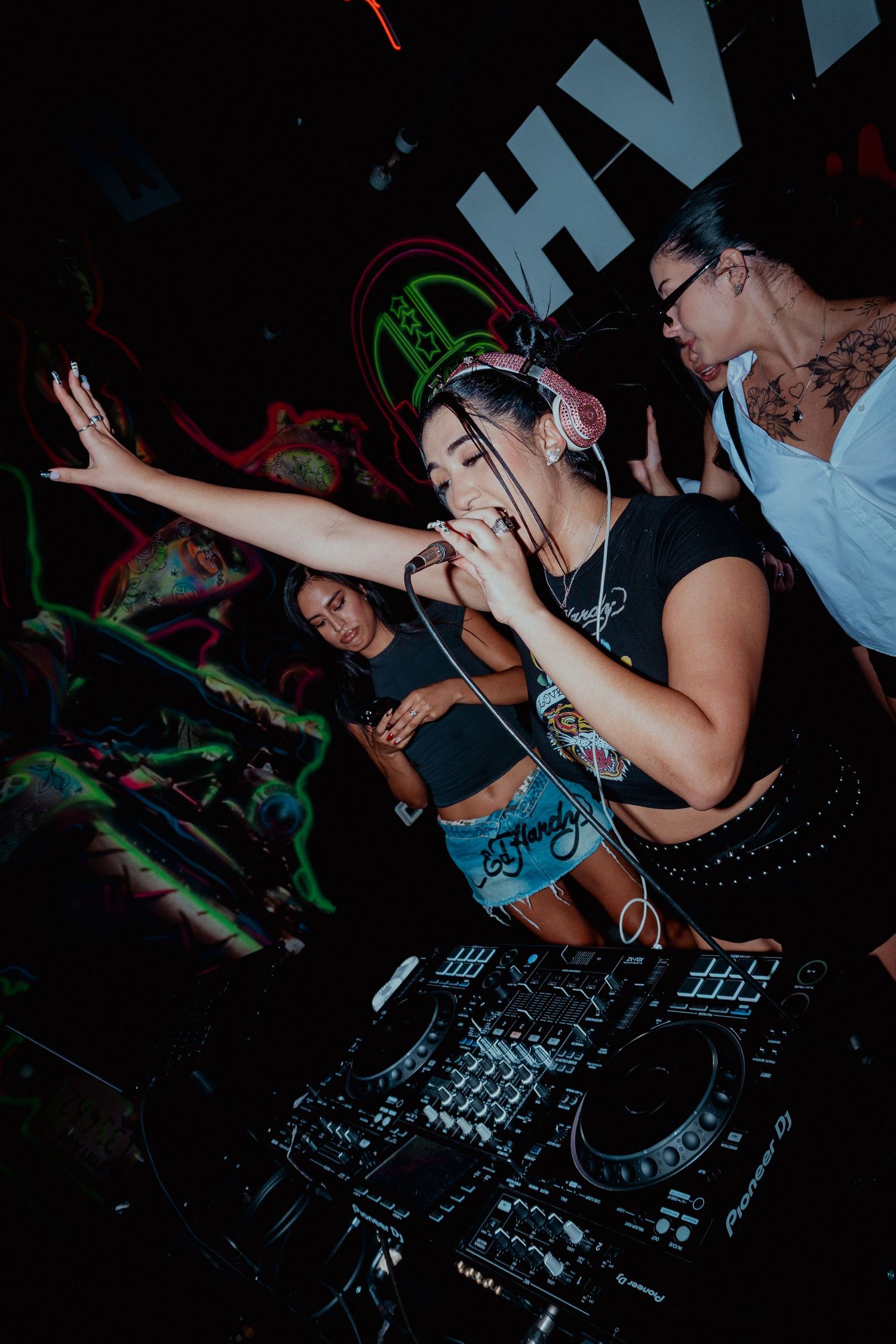 DJ performance at nightclub with crowd and professional mixing equipment.