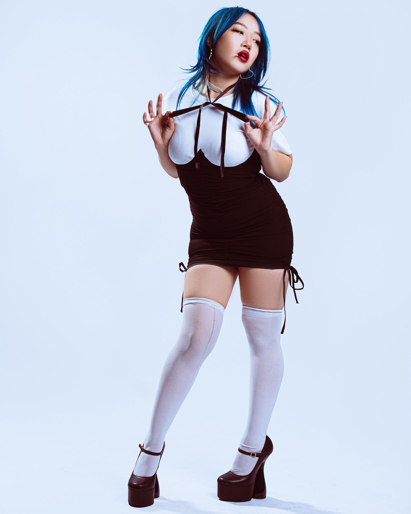 Model in gothic-inspired outfit with blue hair wearing white stockings and platform shoes.