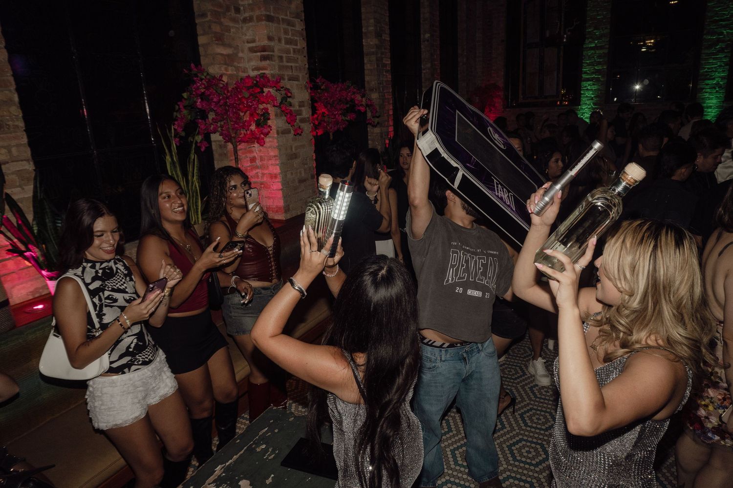 Crowd of people dancing and socializing in a dimly lit nightclub atmosphere.