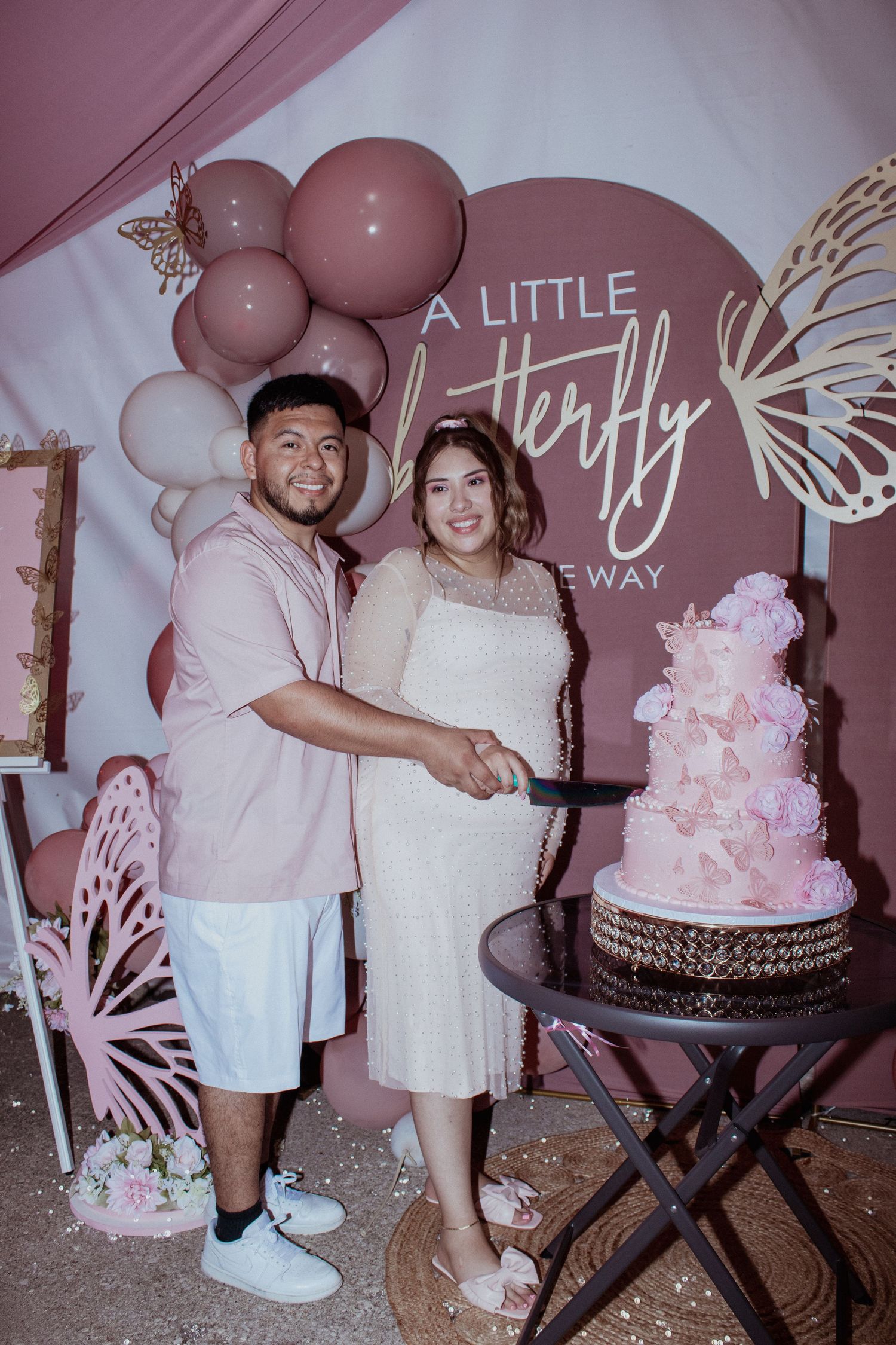 Baby shower celebration featuring a pink tiered cake and butterfly decorations.