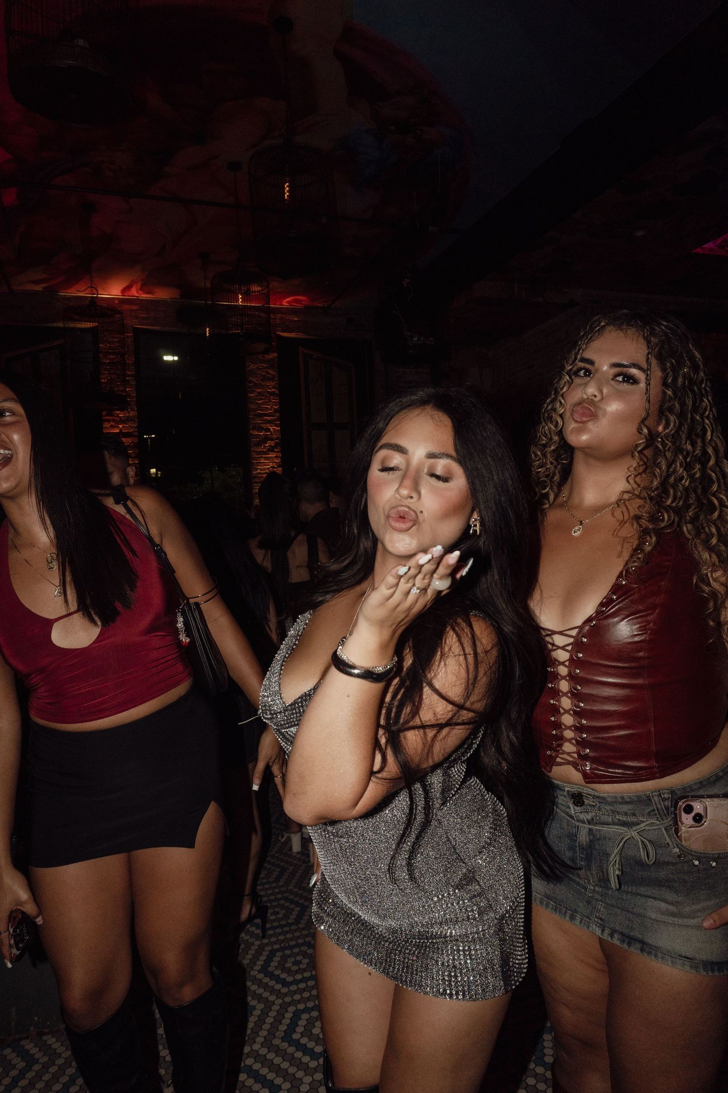 Group of partygoers dancing in a dimly lit nightclub wearing casual attire.