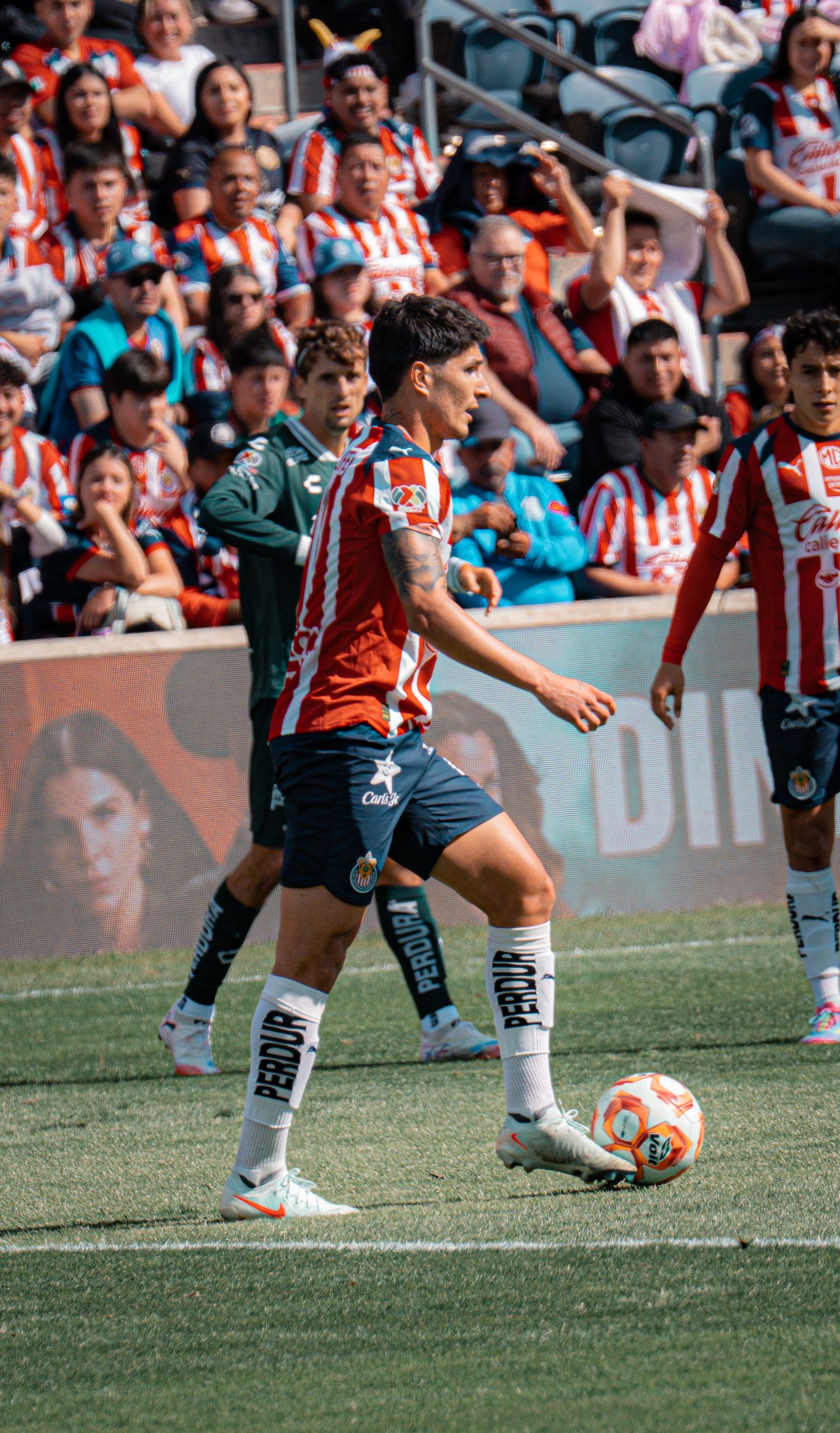 Soccer player in red and white striped jersey controls the ball during a match.