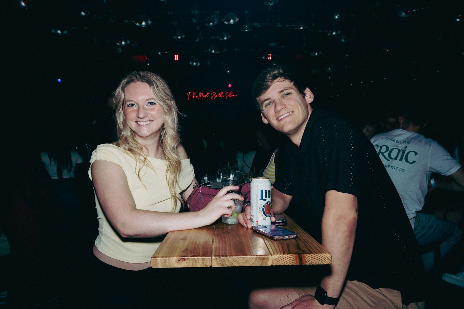 People socializing at tables in a dimly lit bar setting.