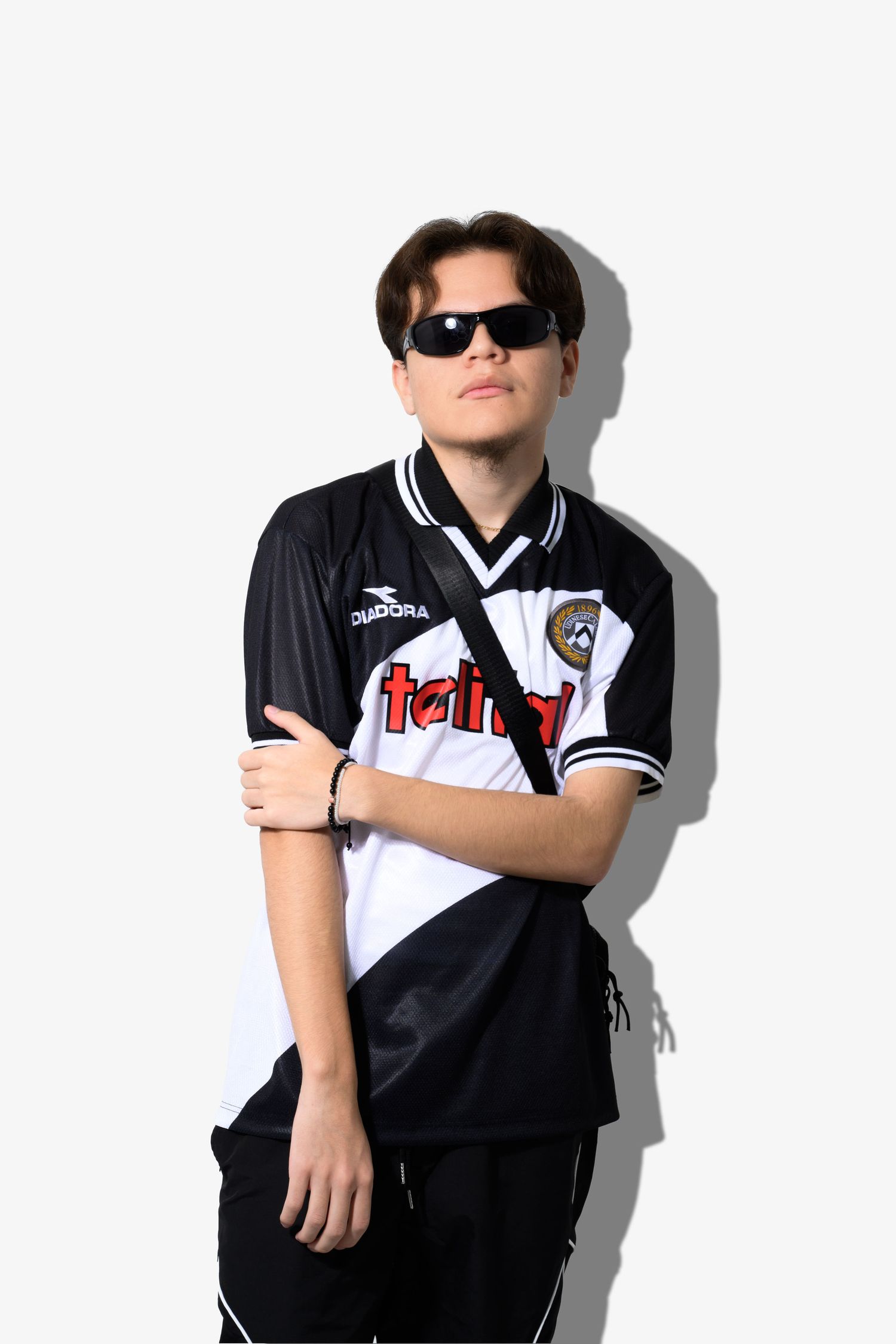 Person wearing sunglasses poses in black and white soccer jersey against white background.