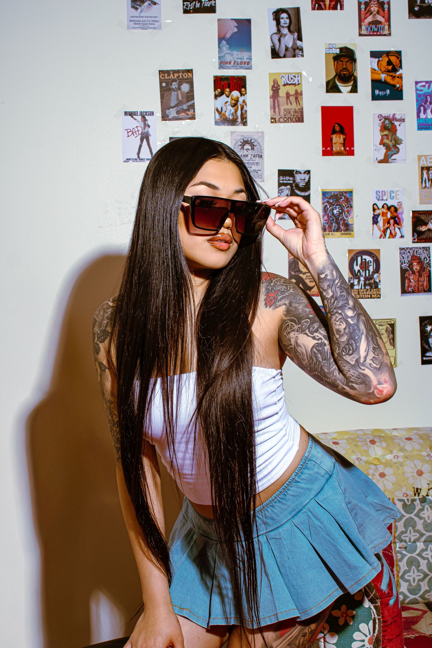 Retro-styled fashion photo with anime posters in background and sunglasses.