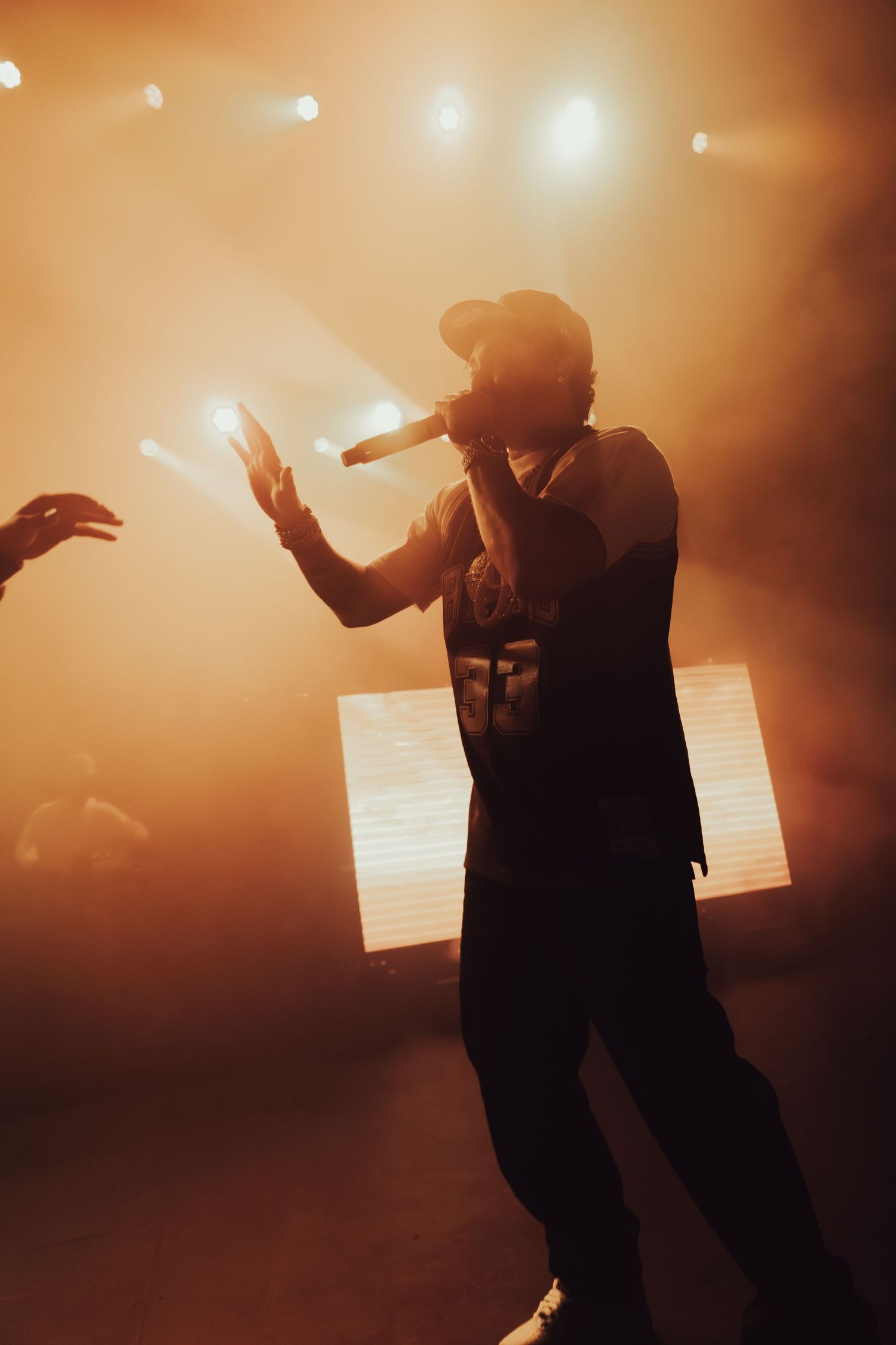 Two performers silhouetted on stage with orange atmospheric lighting effects.