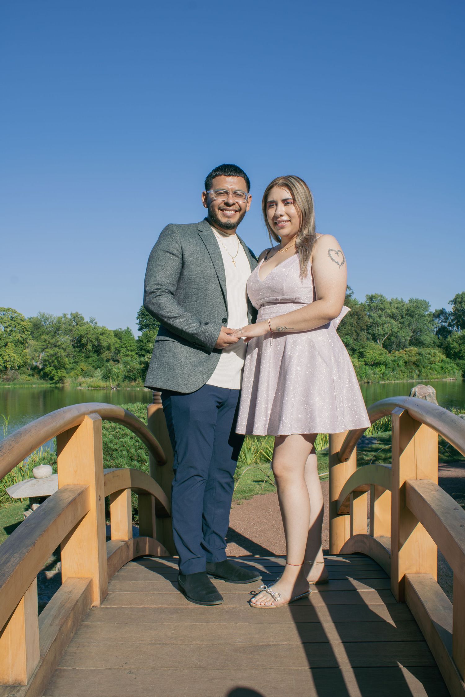 Couple posing together on wooden bridge during outdoor photoshoot.