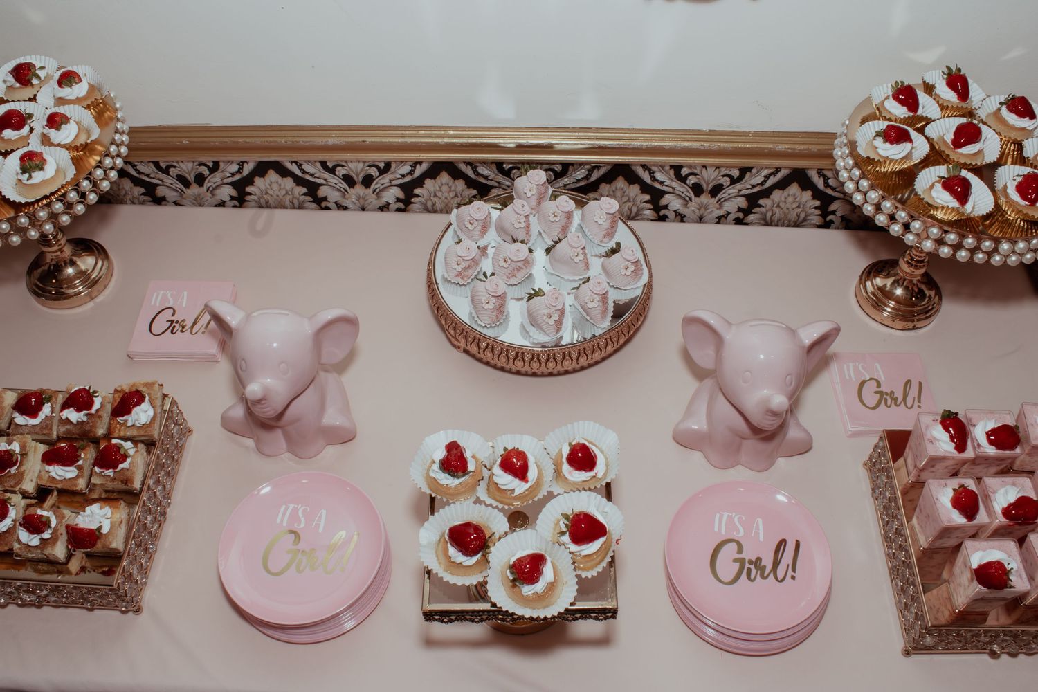 Pink and white dessert table setup with strawberry-topped treats.