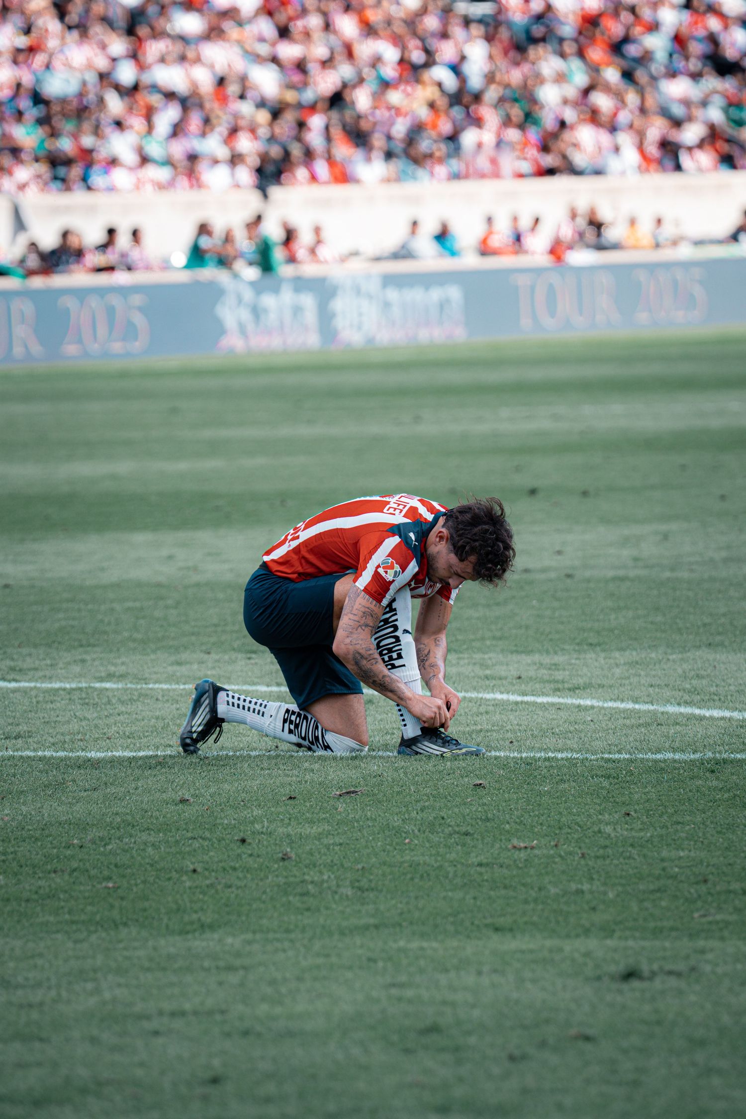 Player in red and white uniform lies on soccer field after a play.