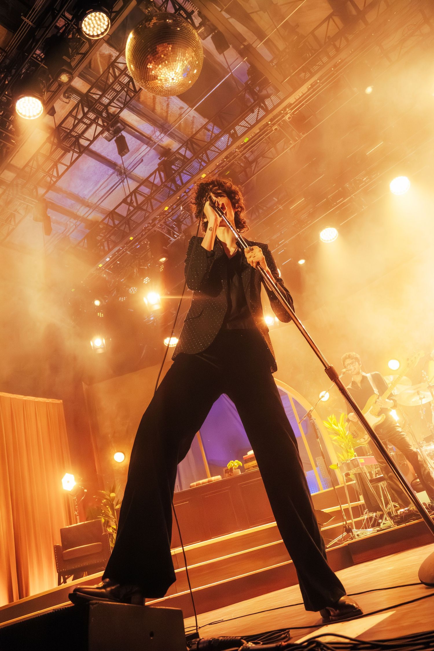 Low-angle concert stage shot with dramatic orange lighting and silhouetted performers creating an atmospheric live music scene.