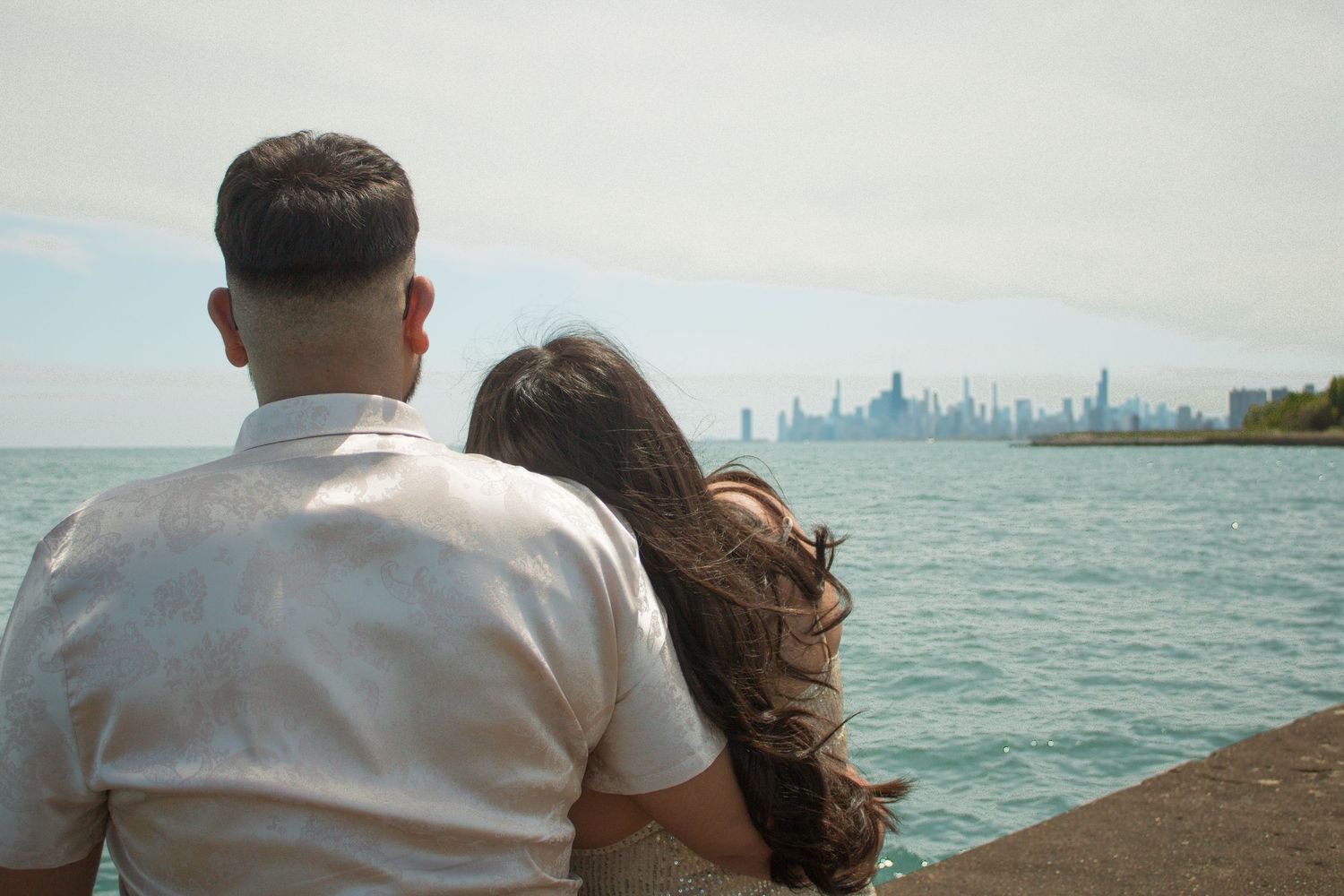 A waterfront engagement photo with the Chicago skyline visible across Lake Michigan.