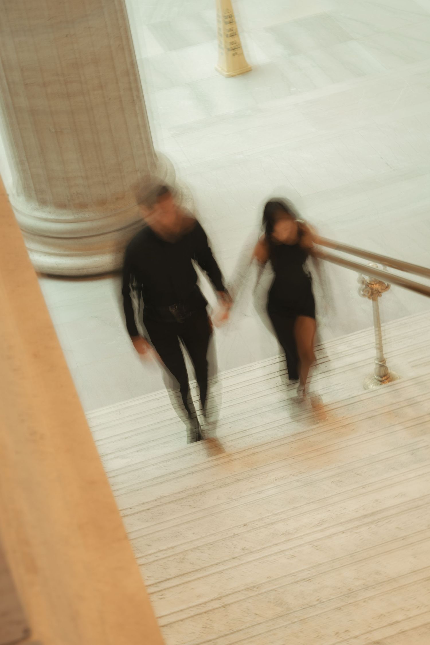 Motion blur photograph of people walking across a light wooden floor.