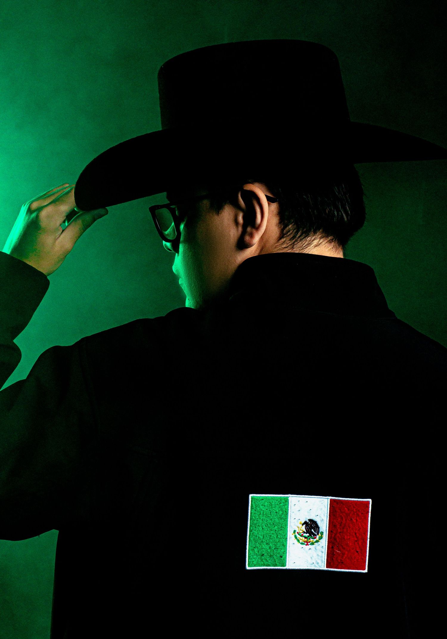 Silhouetted figures against green lighting with Mexican flag emblems visible.