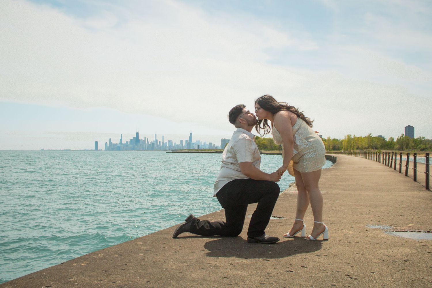A couple shares an intimate moment on a pier with Chicago's skyline visible in the distance.