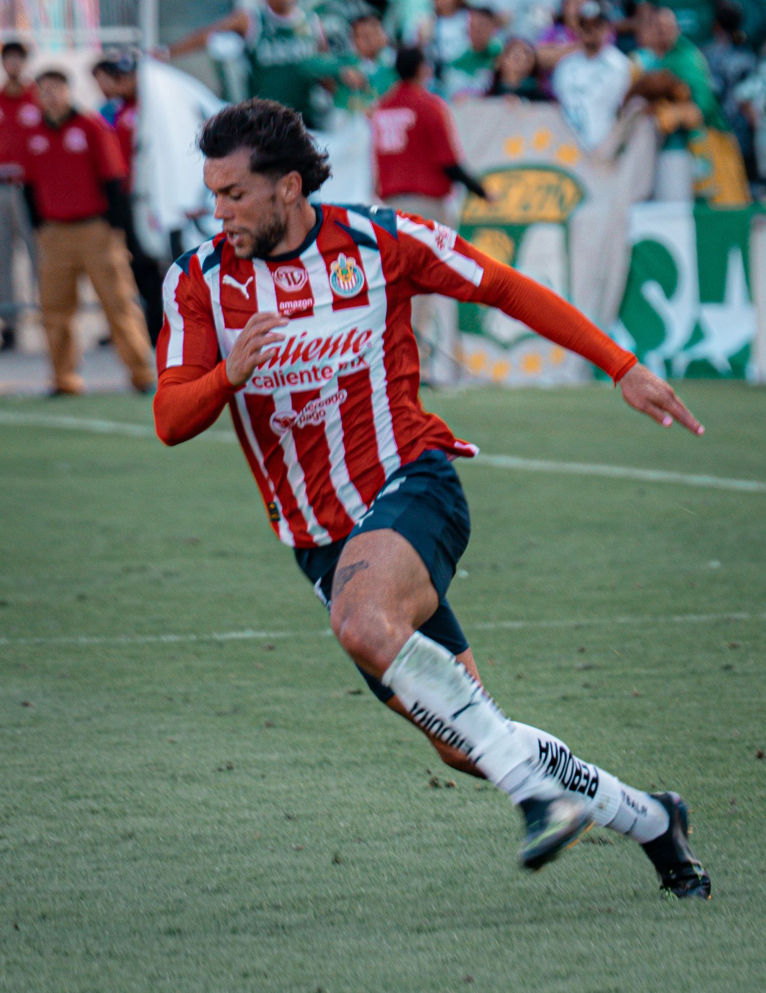 Soccer player in red and white stripes makes dynamic move during game action.