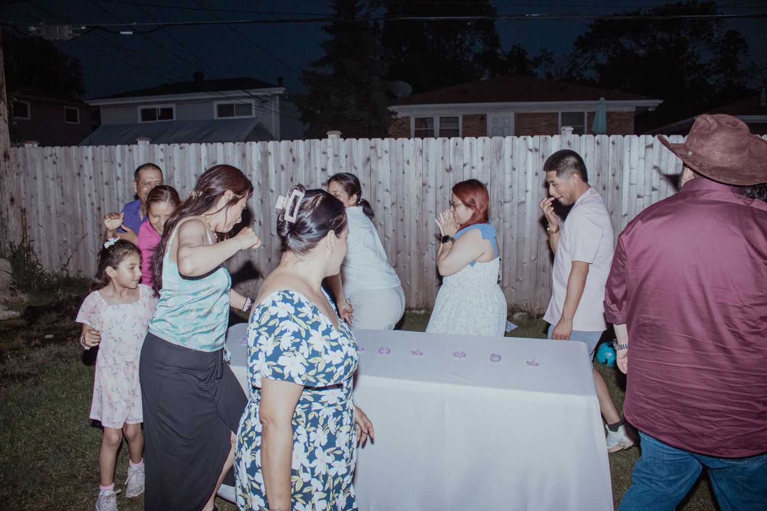Outdoor party scene with people gathered around tables at dusk.