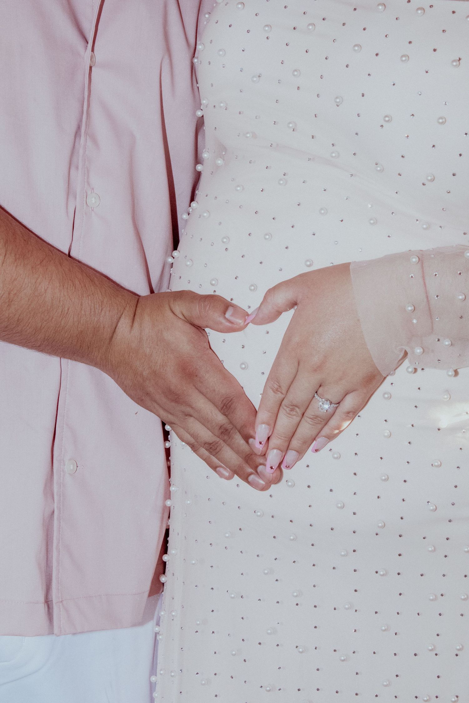 Close-up shots of hands showing engagement or wedding rings against a pink polka dot background.