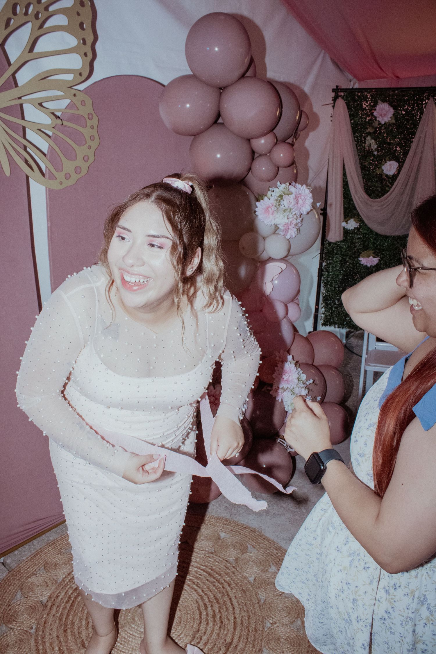 Celebratory gathering with pink balloon decorations and white attire.