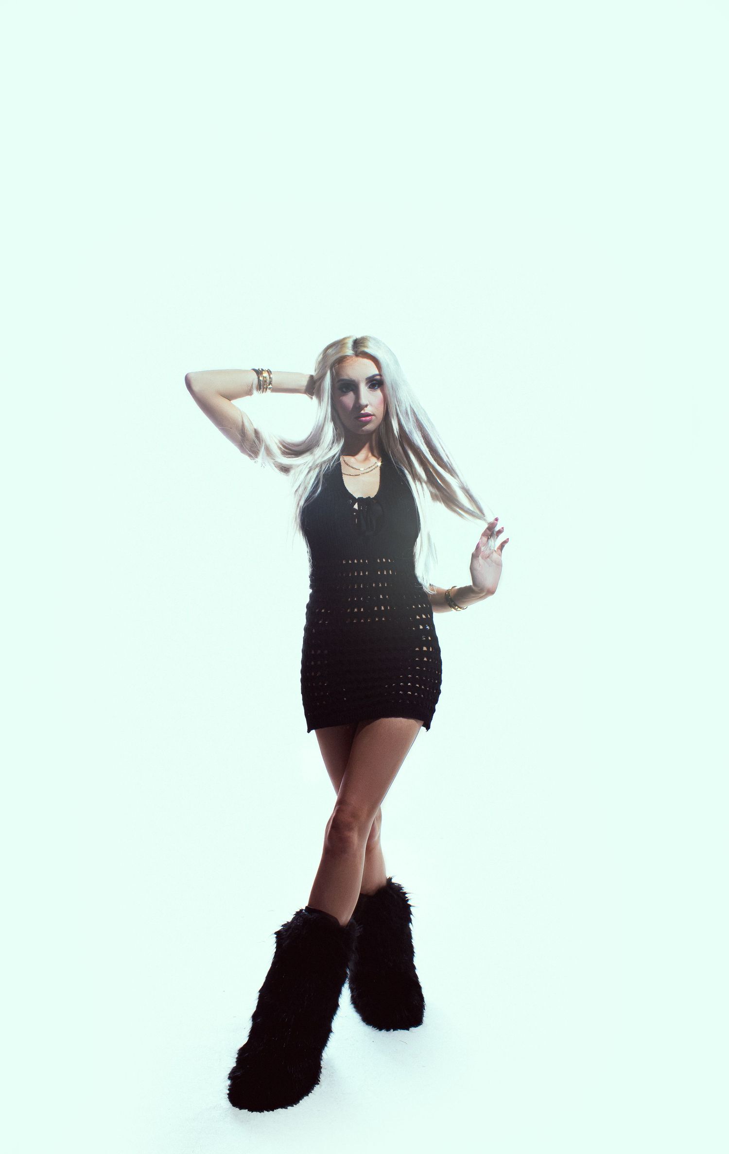 Person in black dress and boots striking dynamic dance poses against white background.