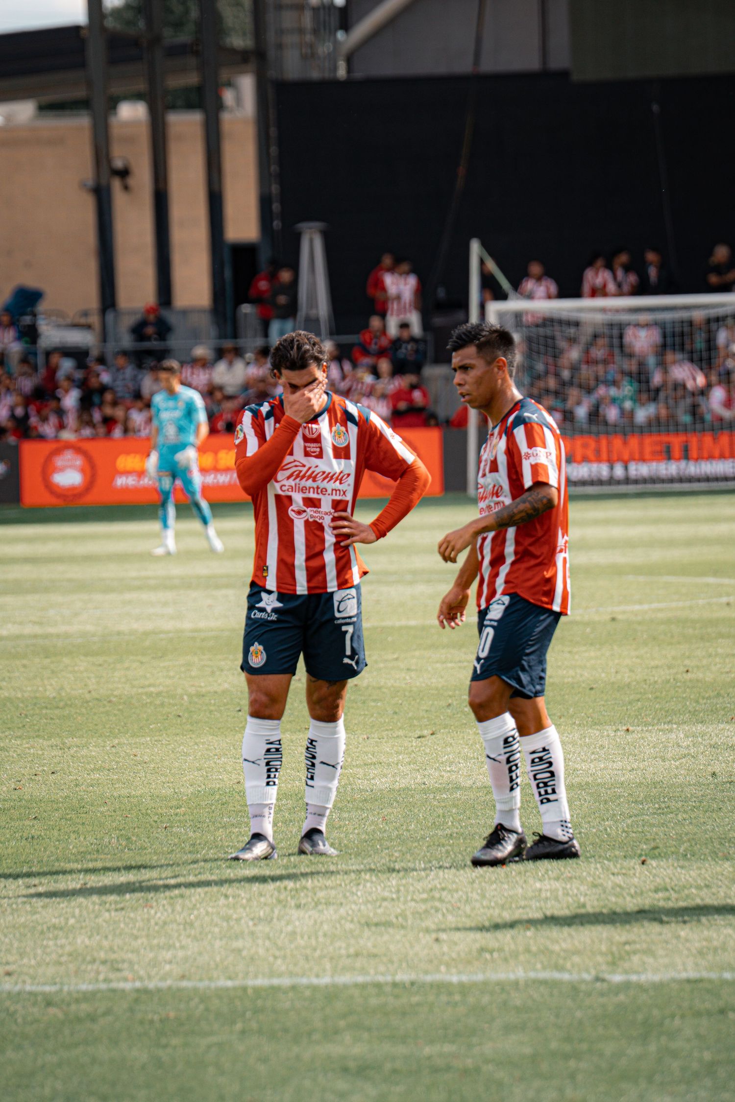 Soccer players in red and white striped jerseys warm up on a grass field before a match.