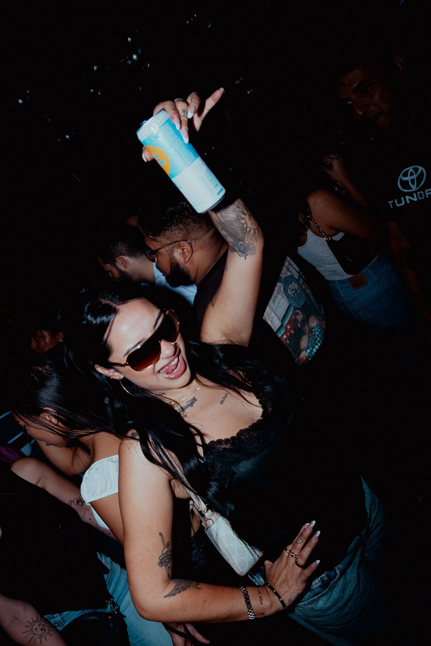 Nightclub patrons dancing and celebrating in dimly lit atmosphere.