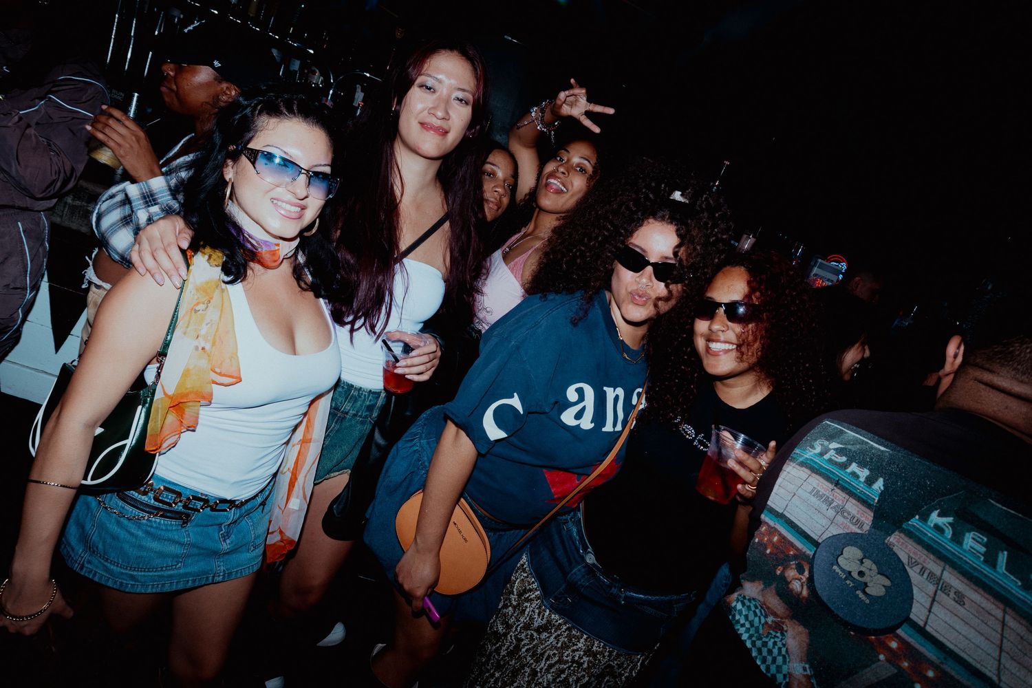 Group of friends enjoying a nighttime party wearing casual summer outfits.