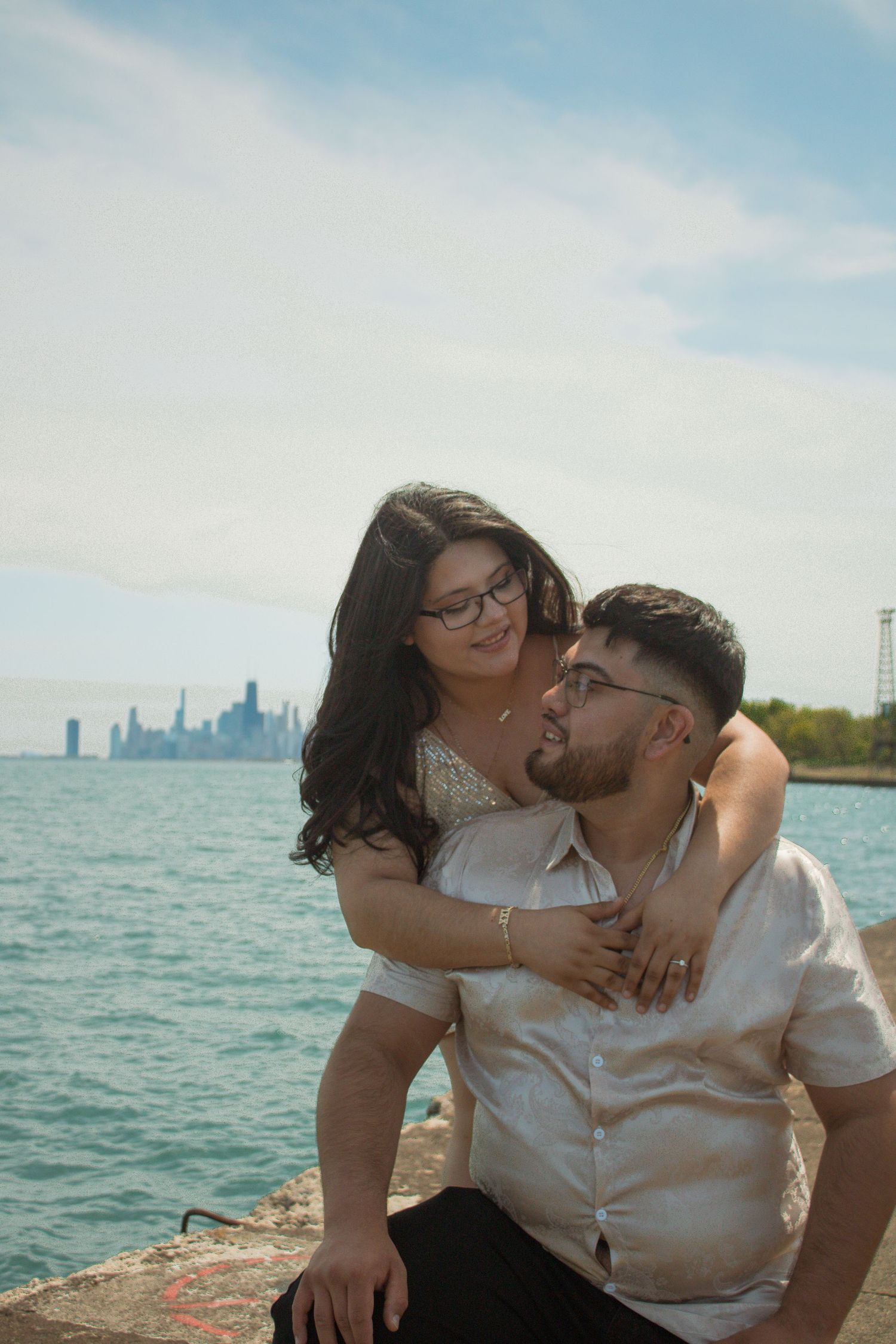 A romantic moment shared between a couple on a pier with the Chicago skyline in the background.