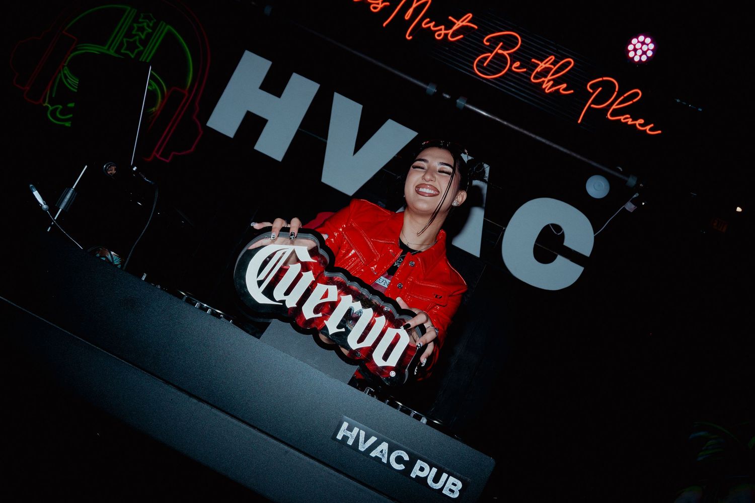 DJ performs at a nightclub with professional equipment and red lighting.