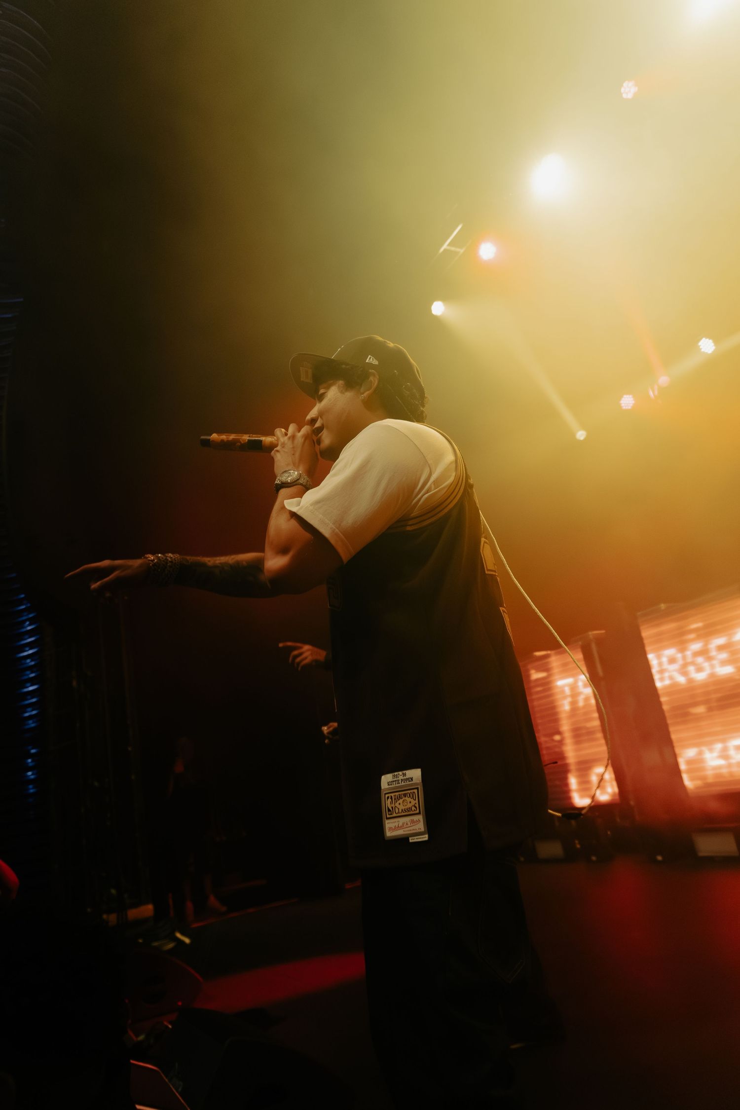 Concert performer in black outfit against warm amber stage lighting.