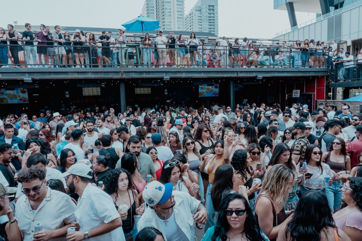 Panoramic view of a packed outdoor festival crowd during daytime.