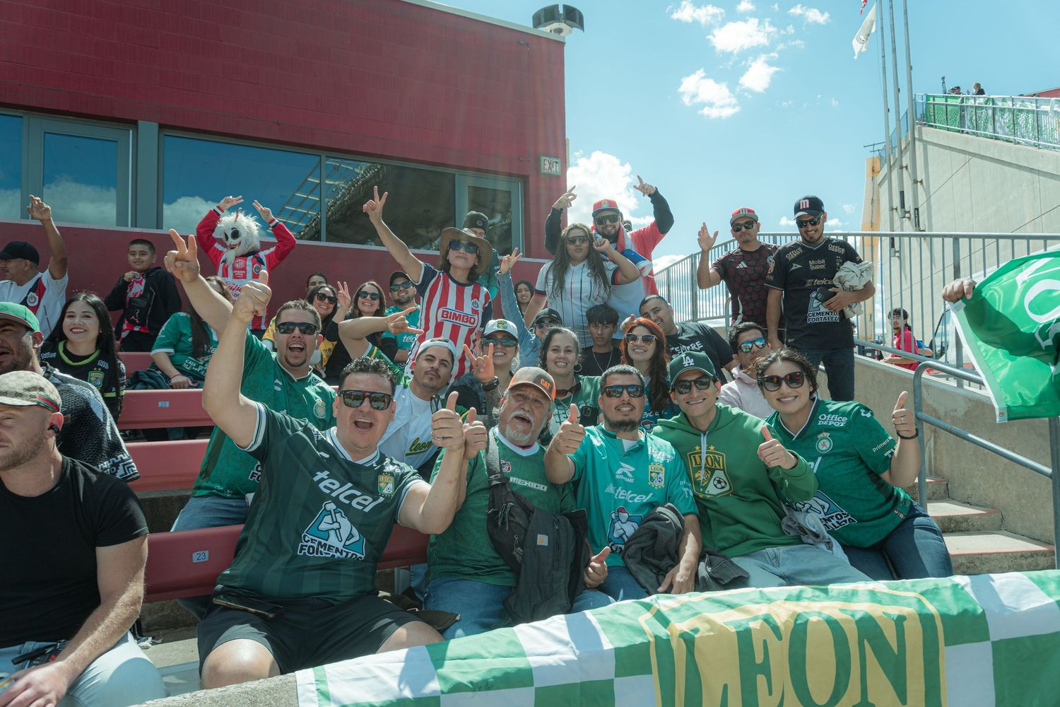 Soccer fans in green jerseys cheer enthusiastically from the stadium stands during a match.
