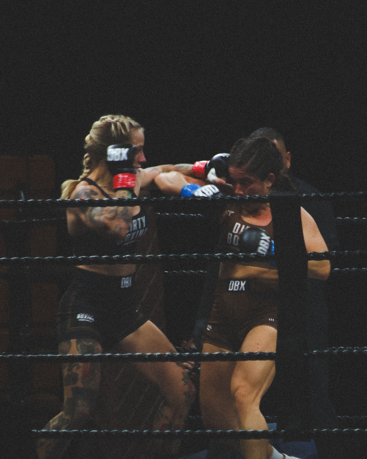 Boxers clinch while throwing punches in a professional fight.