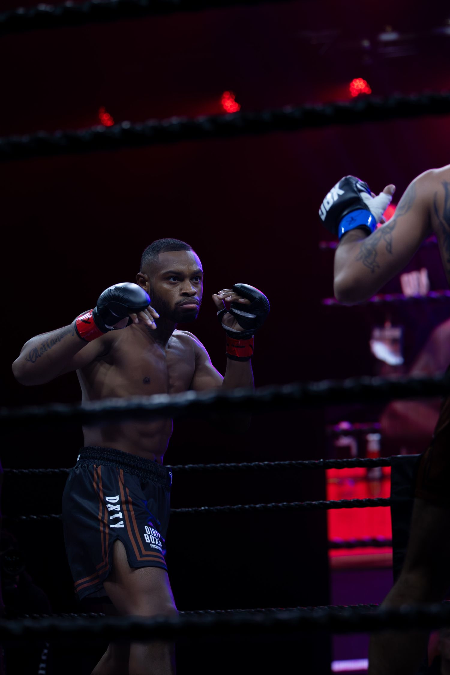 A boxer in defensive stance during a match under dramatic lighting.