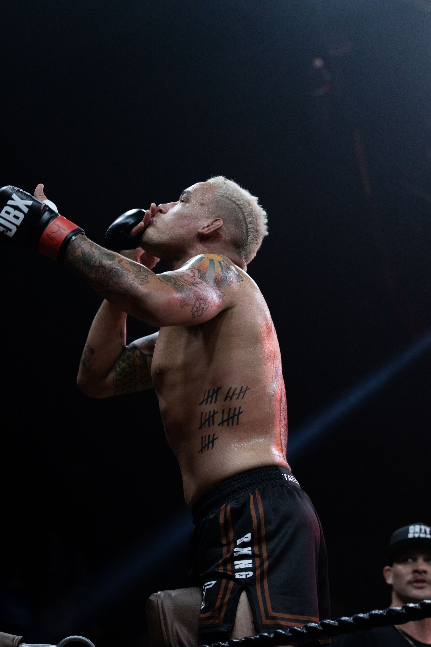 Shirtless performer sings passionately on stage under dramatic lighting at a concert venue.
Byan Battle