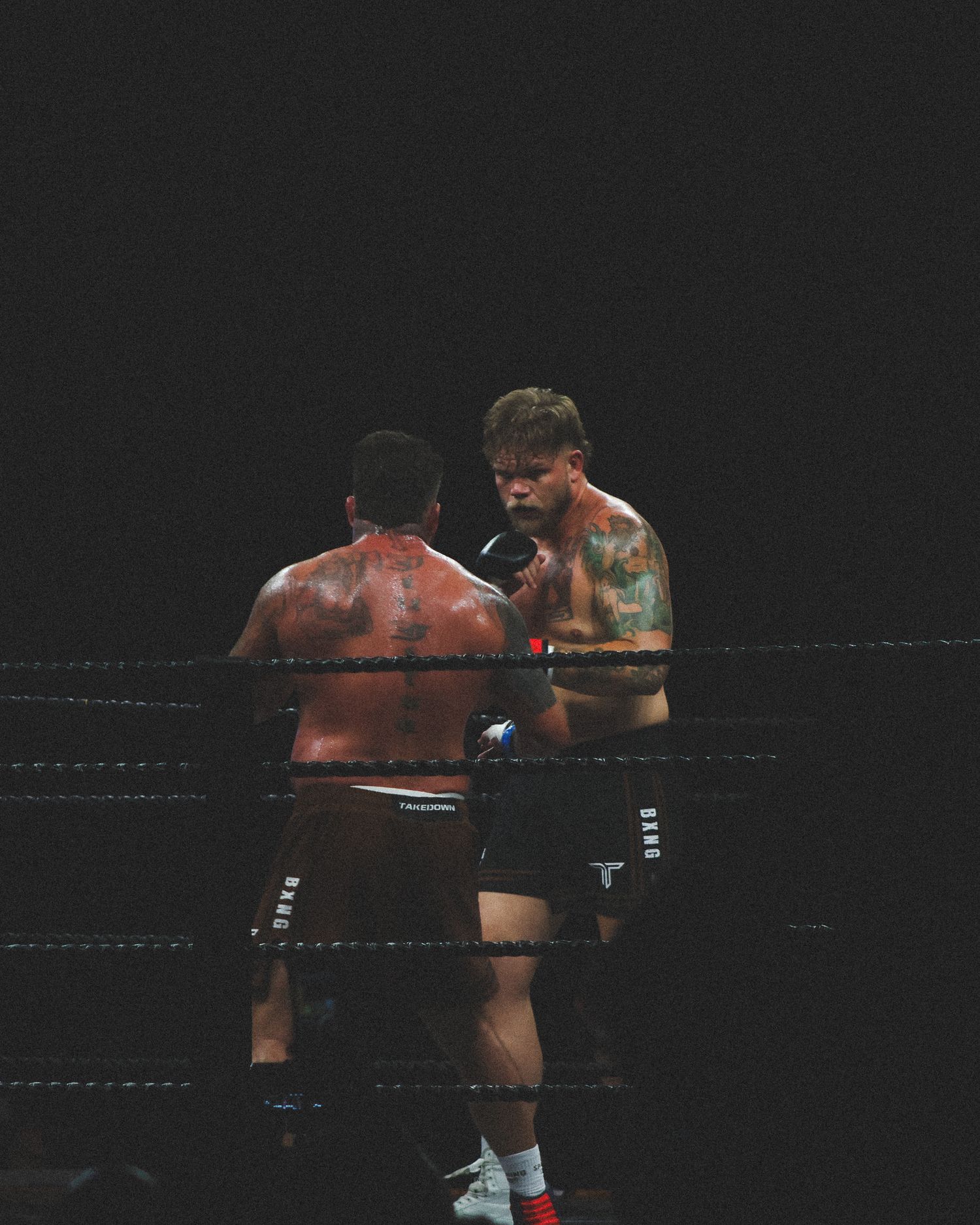 Two fighters trade blows in close combat during a professional boxing match.