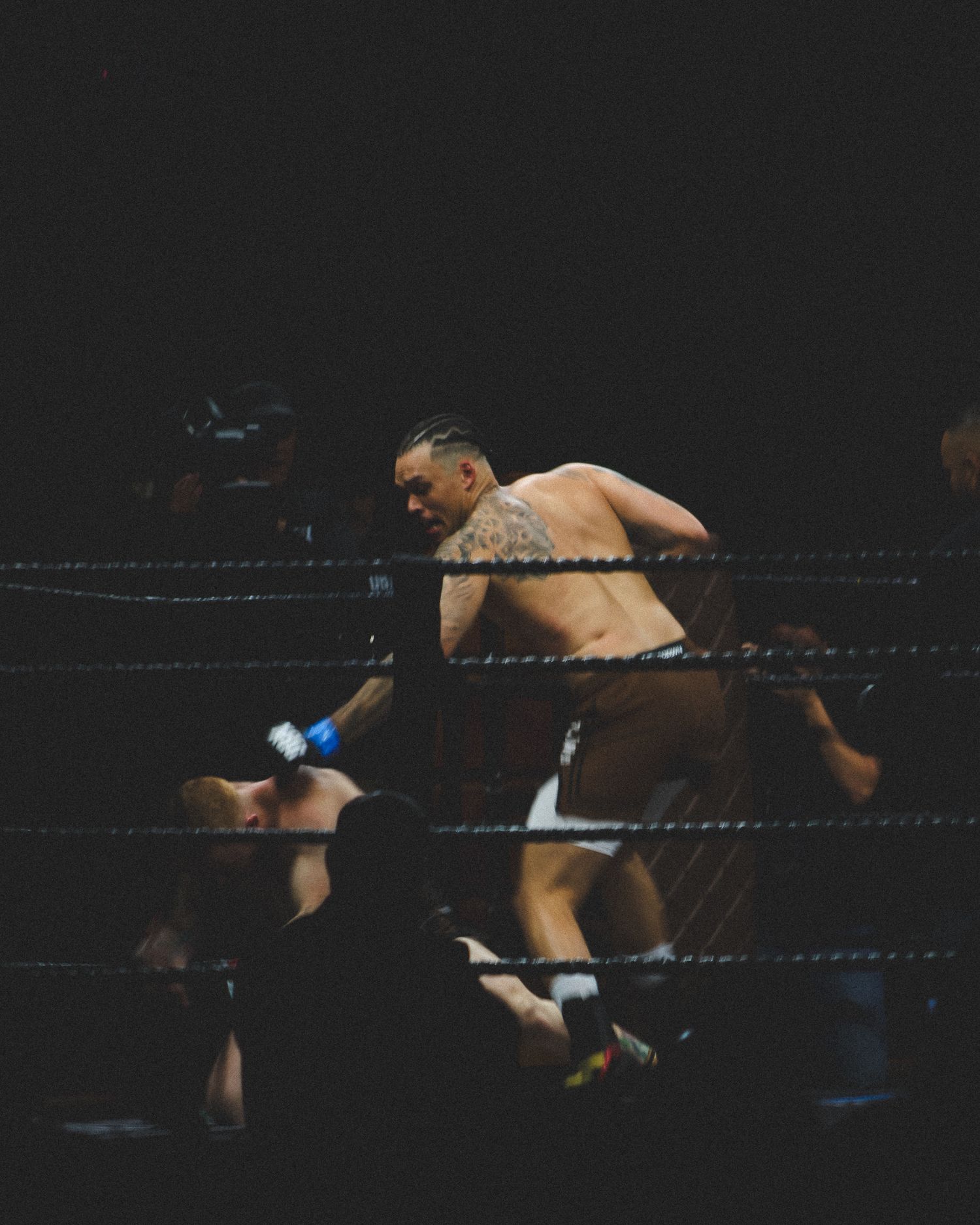 A boxer throws a powerful punch while leaning over the ropes during an intense match.