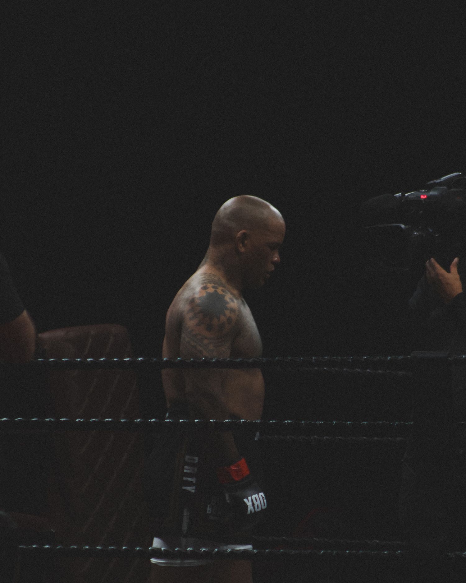 Two boxers compete in a dimly lit professional boxing ring.