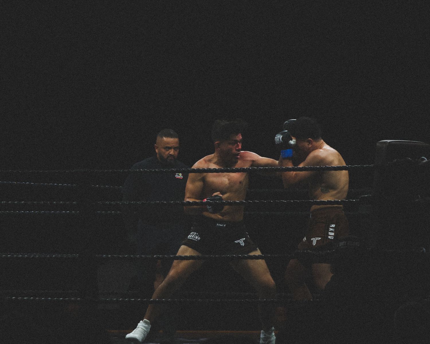 Two competitors exchange strikes during a professional boxing bout.