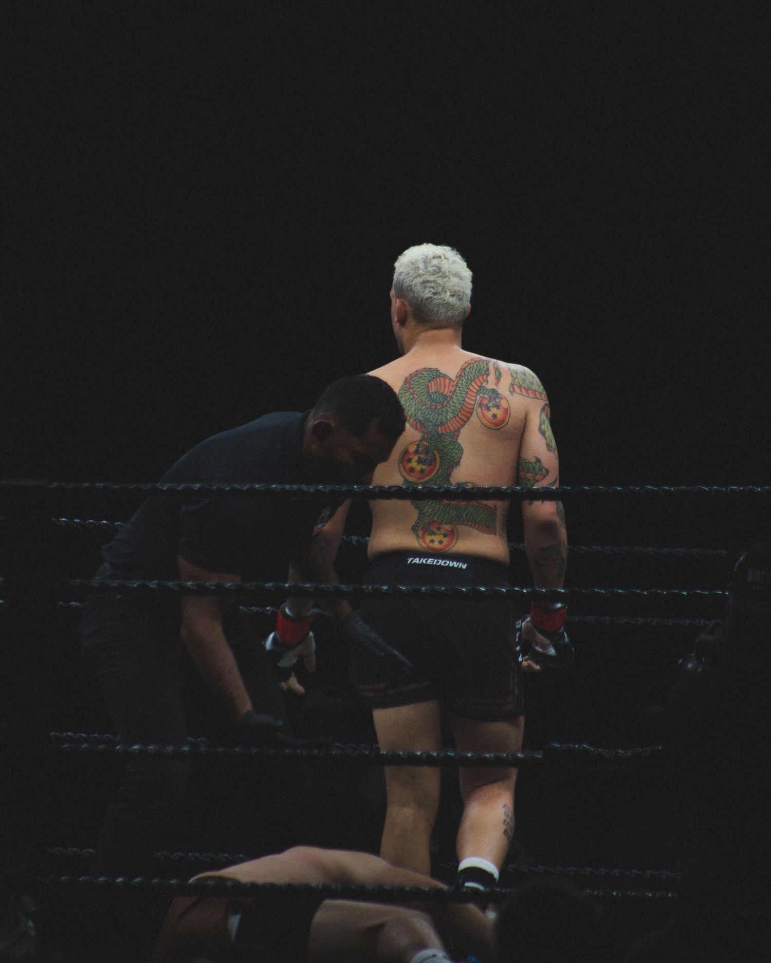 A boxer with visible tattoos stands in defensive position during a match.
