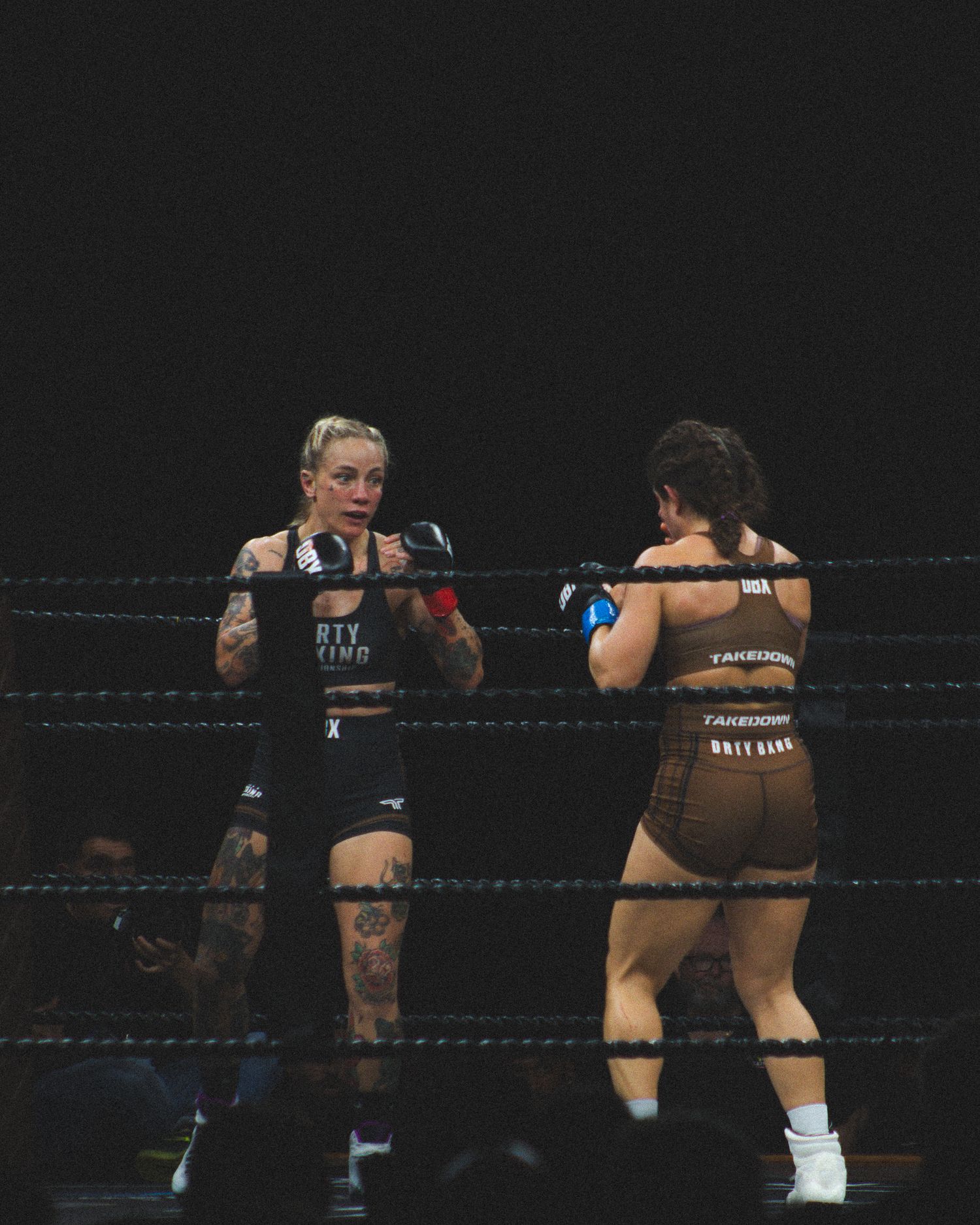 Athletes engage in a fierce boxing exchange under dramatic lighting.