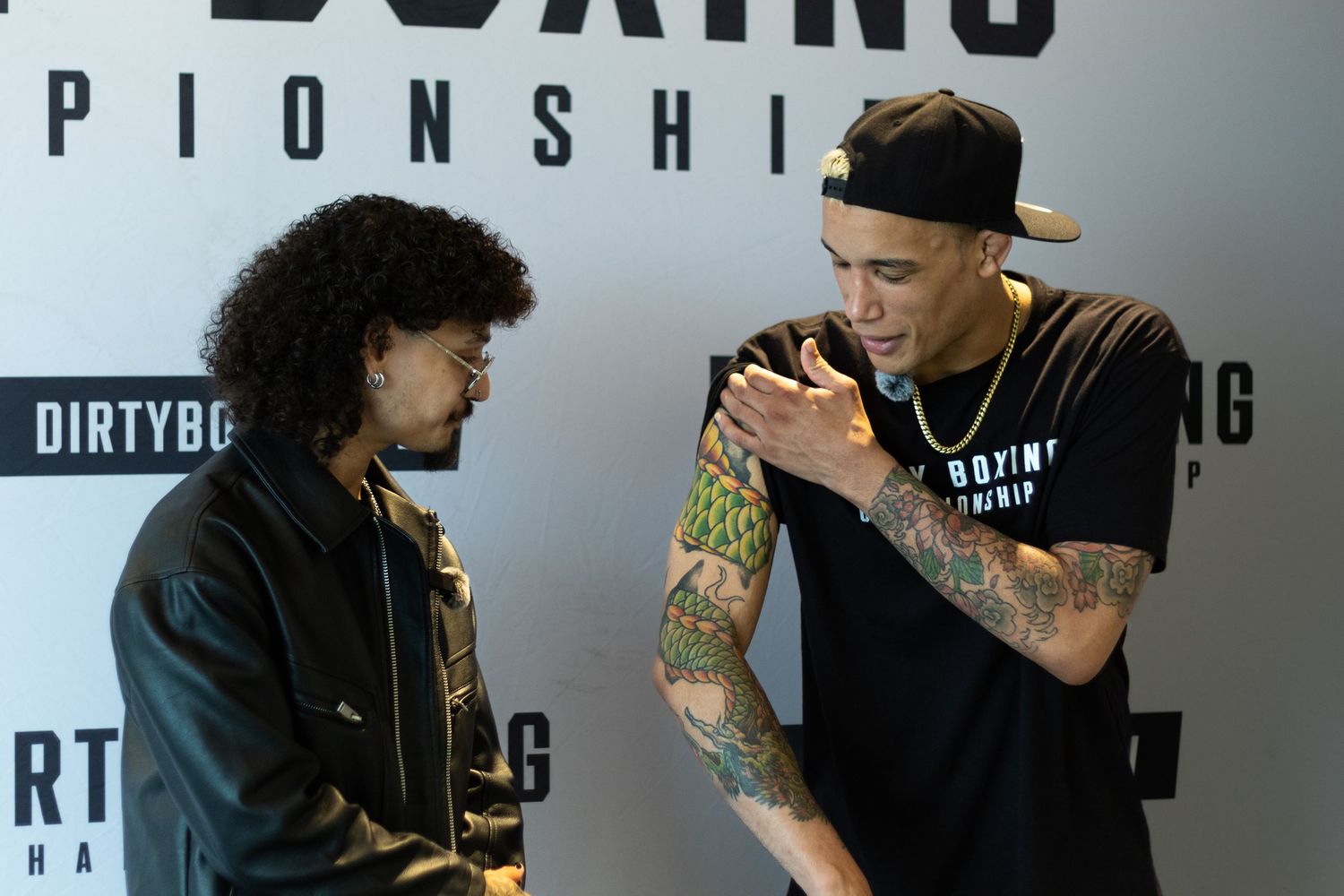 Two boxers greet each other warmly at a boxing event press conference.